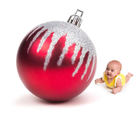 Cute Baby smiling at a Huge Christmas Ornament on whiteの写真素材