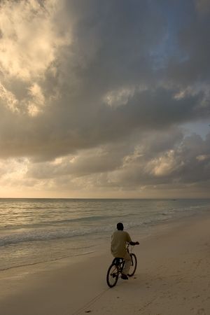 man cycling by zanzibar's beach at the sunsetの写真素材