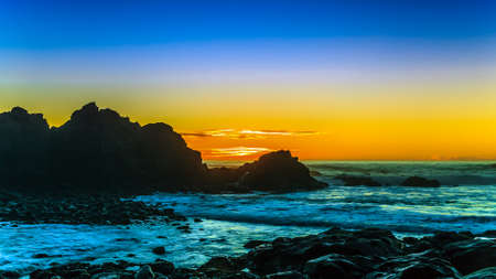 Rocky yellow sunset at shoreの写真素材