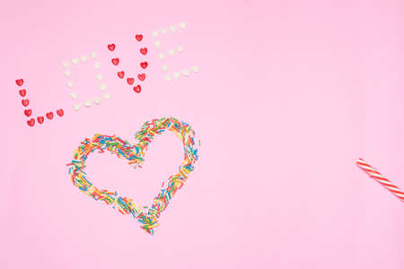 Pink background, confetti forming heart and love lettering.の写真素材