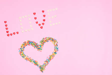 Pink background, confetti forming heart and love lettering.の写真素材