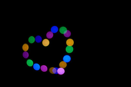 black background with defocused lights forming a heart.の写真素材