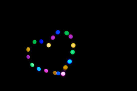 black background with defocused lights forming a heart.の写真素材