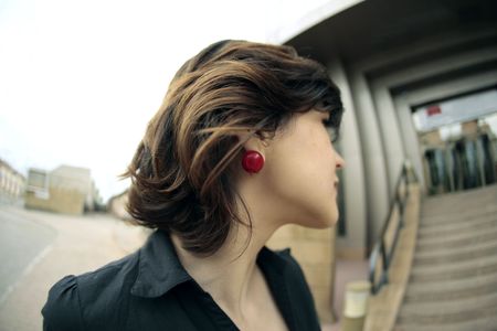 young business woman looking at a building's stairs with her red earring in the center of the image の写真素材