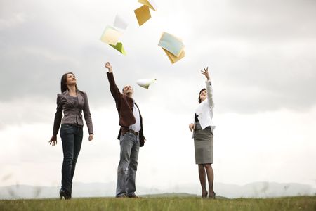 Young team shouting their victory to the world by trowing documents/ paper in the air outdoors