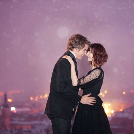 Profile of Romantic Couple smiling looking into each others eyes against the city at night on valentine's dayの写真素材