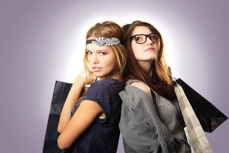 Attractive and cool looking teenage girls with headpieces holding shopping bags on gradient backgroundの写真素材