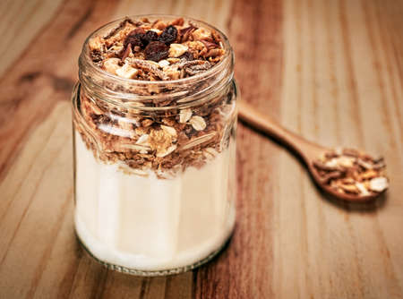Cereals on wooden table with wooden spoon in glassの写真素材