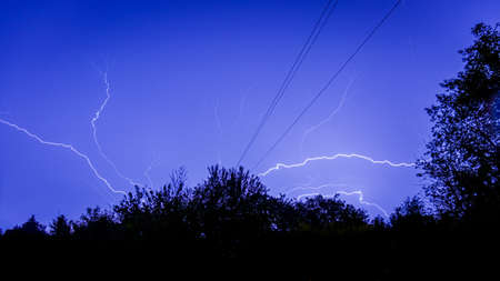 Branching lightning strikes at night over the horizon
