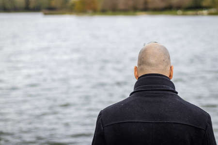 A man stands on the lake shore in bad weatherの写真素材