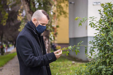 A man walks in the dripping rain while wearing a mask in a small city in Hungaryの写真素材