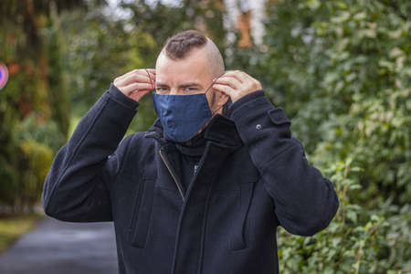 A man puts on his mask in the dripping rain in a small city in Hungaryの写真素材