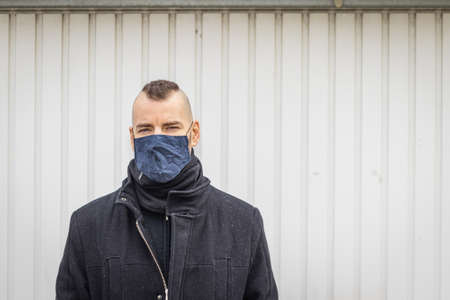 A man stands in front of garages in a mask in a small city in Hungary