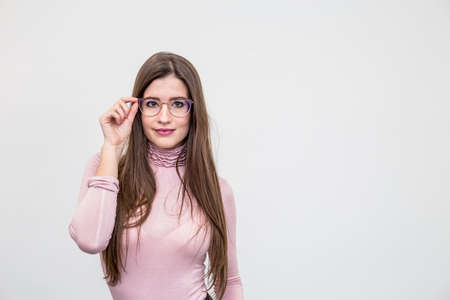 Beautiful young smiling woman with glasses standing over white wallの写真素材
