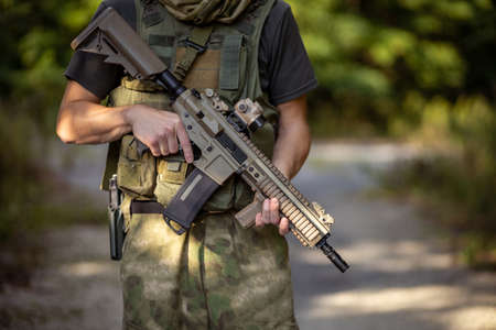 Close up of a man standing with an airsoft assault rifle in military uniformの写真素材