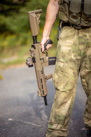 Close up of a man holding an airsoft assault rifle in military uniformの写真素材