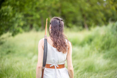 A Hungarian woman in a linen dress standing with a bow on the fieldの写真素材