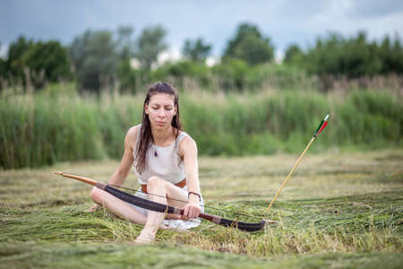 A Hungarian woman in a linen dress sitting in the field with a bowの写真素材