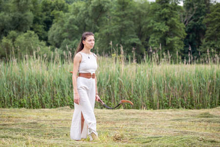 A Hungarian woman in a linen dress with a bow is walking on the fieldの写真素材