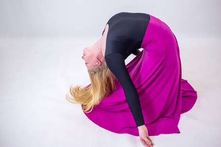 Young blonde blue-eyed dancer woman in long purple skirt on white backgroundの写真素材