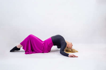 Young blonde blue-eyed dancer woman in long purple skirt on white backgroundの写真素材