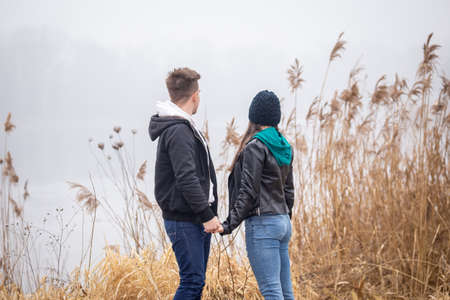 Young couple standing by a lake on a foggy winter dayの写真素材