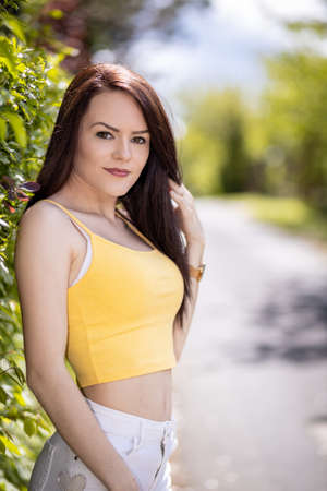 Portrait of a young woman in yellow top and white shorts in summerの写真素材