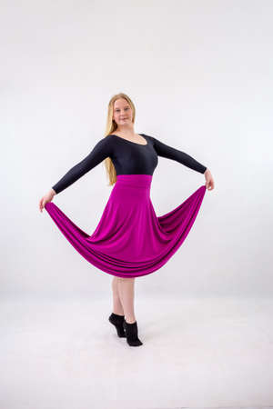 Young blonde blue-eyed dancer woman in long purple skirt on white backgroundの写真素材