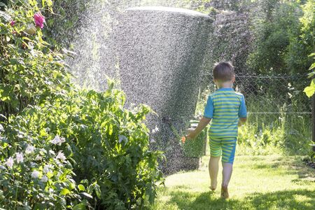 Little boy runs through water splashes. summer outdoor.の写真素材