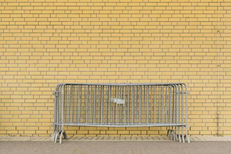Metal fences in front of a yellow brick wall on a construction siteの写真素材
