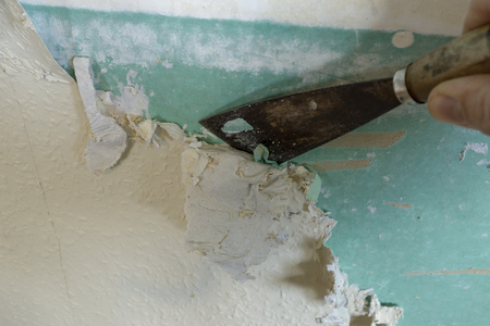 Hands removing old wallpaper with the help of a spatula during the repair in the room. Close-up.の写真素材