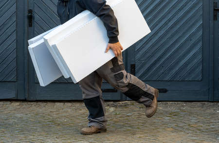 Man running, holding pile of boxes, side viewの写真素材