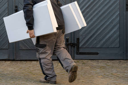 Man running, holding pile of boxes, side viewの写真素材