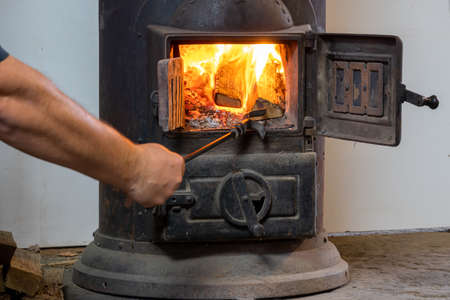 Man putting log to wood burning stoveの写真素材