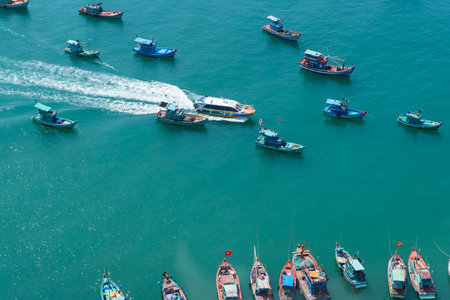 A boat is sailing in the middle of a large body of water, surrounded by many other boats. The boat...