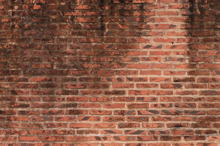 A brick wall with a brown color. The wall is made of bricks. The wall is old and has a lot of dirt...