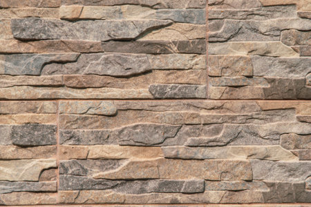 The wall is made of stone and has a brown and gray color. It is a very rough and textured surface,...