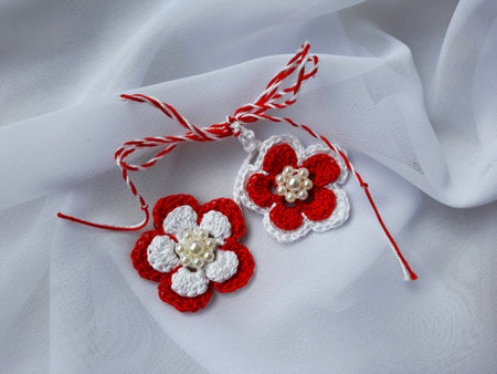 Handmade crocheted flower with red and white string, known as Martisor. It is a Romanian traditional symbol of the beginning of spring. Isolated on white background.の写真素材