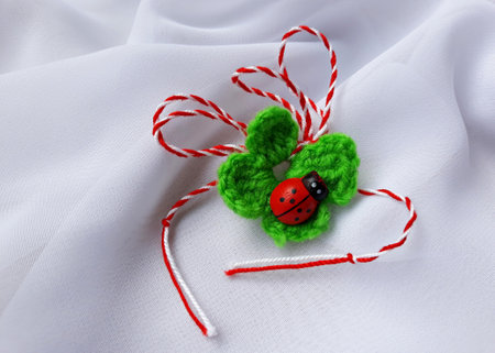 Handmade crocheted four-leaf clover with ladybug and red and white string, known as Martisor. It is a Romanian traditional symbol of the beginning of spring. Isolated on white background.の写真素材
