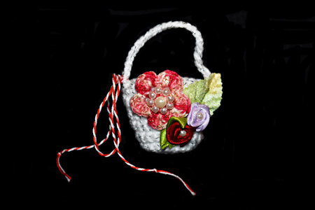Handmade crocheted basket with red and white string, known as Martisor. It is a Romanian traditional symbol of the beginning of spring. Isolated on black background.の写真素材