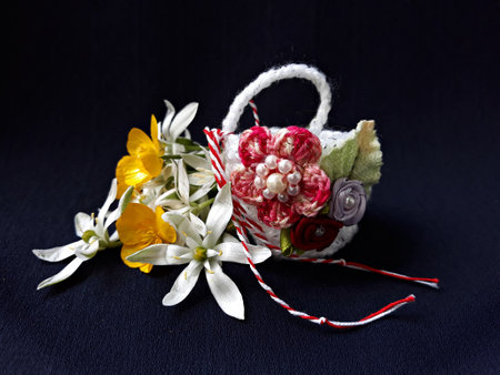 Handmade crocheted basket with red and white string, known as Martisor. It is a Romanian traditional symbol of the beginning of spring. Isolated on black background.の写真素材