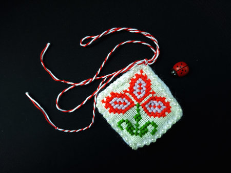 Traditional sewing pattern with red and white string, known as Martisor. It is a Romanian traditional symbol of the beginning of spring. Isolated on black background.の写真素材