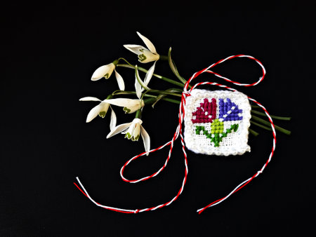 Traditional sewing pattern with red and white string, known as Martisor. It is a Romanian traditional symbol of the beginning of spring. Isolated on black background.の写真素材