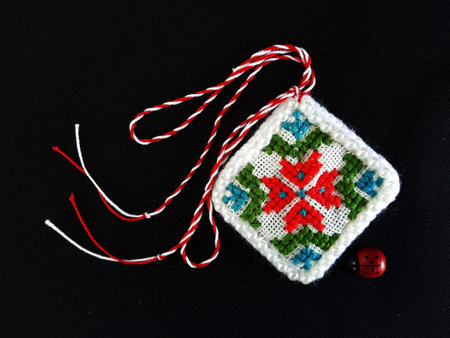 Traditional sewing pattern with red and white string, known as Martisor. It is a Romanian traditional symbol of the beginning of spring. Isolated on black background.の写真素材