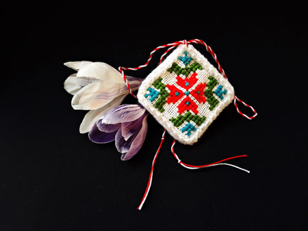 Traditional sewing pattern with red and white string, known as Martisor. It is a Romanian traditional symbol of the beginning of spring. Isolated on black background.の写真素材