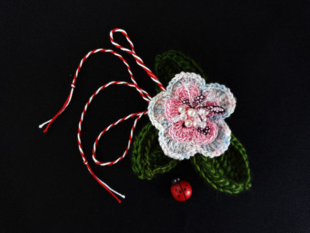 Handmade crocheted flower, with red and white string, known as Martisor. It is a Romanian traditional symbol of the beginning of spring. Isolated on black background.の写真素材