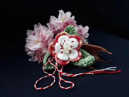 Handmade crocheted flower, with red and white string, known as Martisor. It is a Romanian traditional symbol of the beginning of spring. Isolated on black background.の写真素材