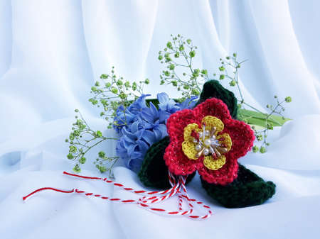 Handmade crocheted flower, with red and white string, known as Martisor. It is a Romanian traditional symbol of the beginning of spring. Isolated on white background.の写真素材