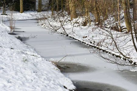 Snowy winter landscape with frozen lake, in the city park.の写真素材