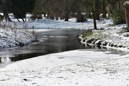 Snowy winter landscape with frozen lake, in the city park.の写真素材
